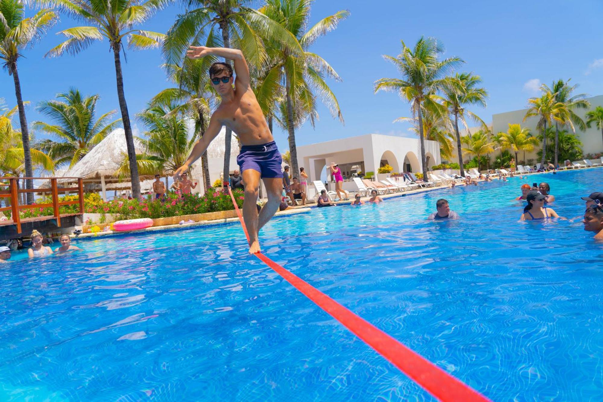 Grand Oasis Cancun Hotel Exterior photo A man walking on a slackline over a pool